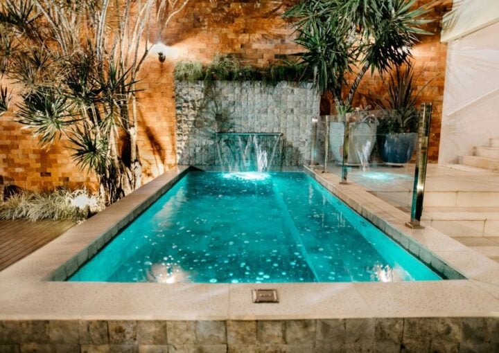 A crystal-clear turquoise pool in a beautifully landscaped backyard