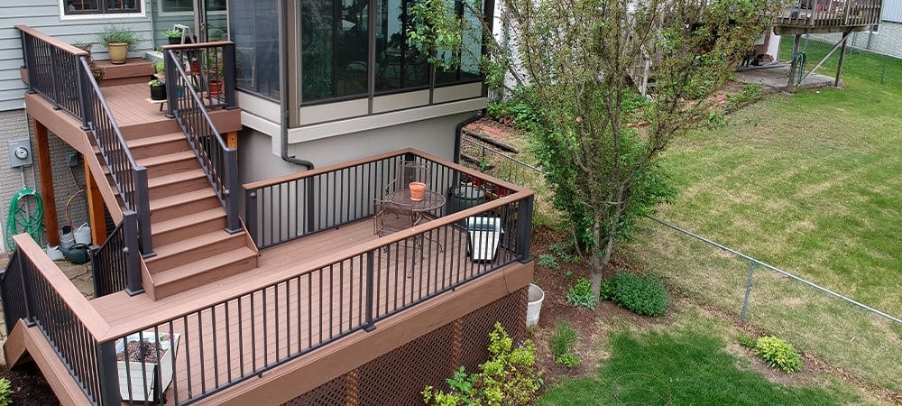 multi level wooden deck with stairs and rail in home backyard