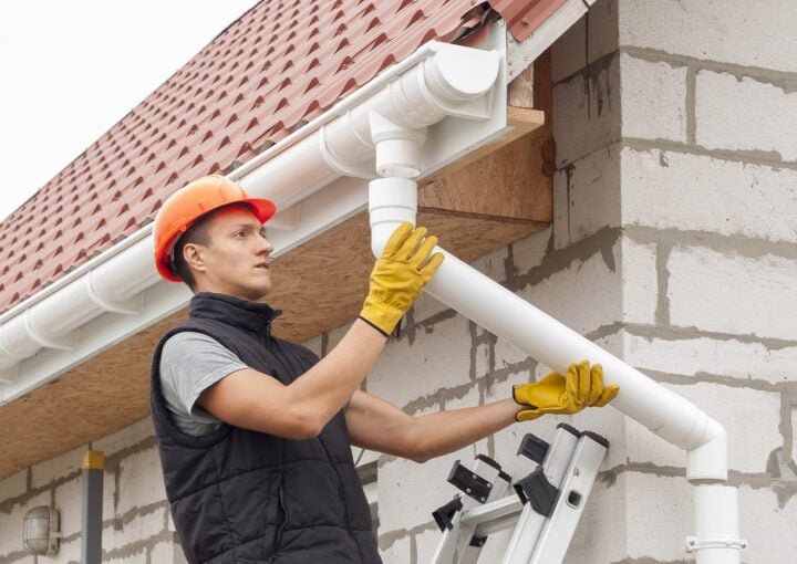construction worker installs the gutter system on the roof