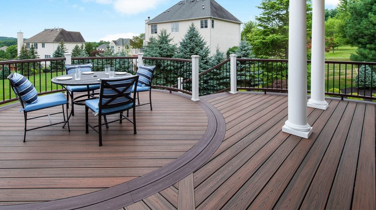 Curved composite deck with dining set and elegant railing, offering scenic suburban views.