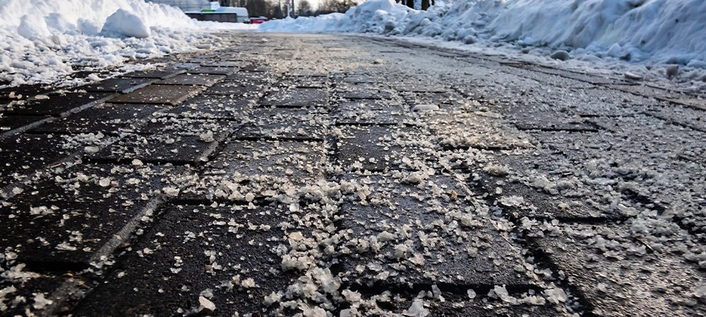 salt grains on icy sidewalk surface in the winter