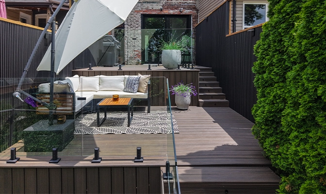 modern deck with complete setup, umbrella on coach, glass railing, multi steps deck, open in home backyard