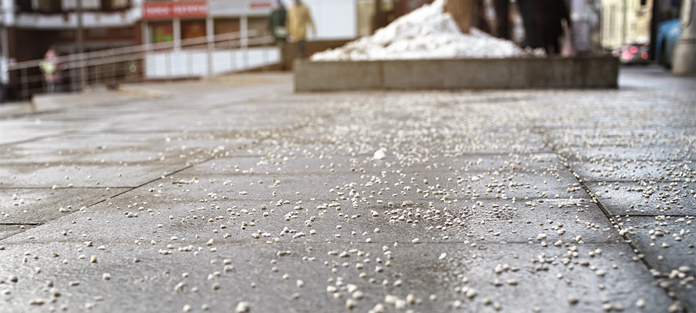 pavement of city street near bus stop is sprinkled with salt and calcium