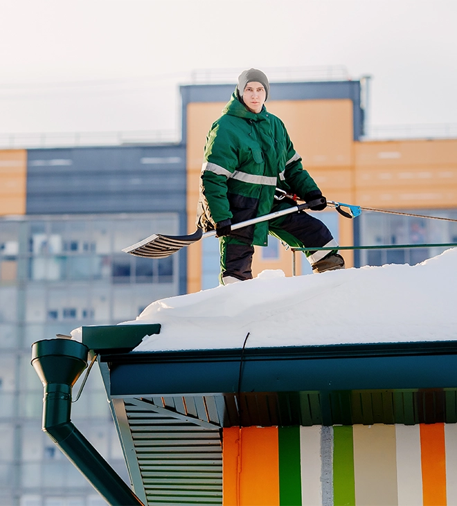 professional man removing snow from roof