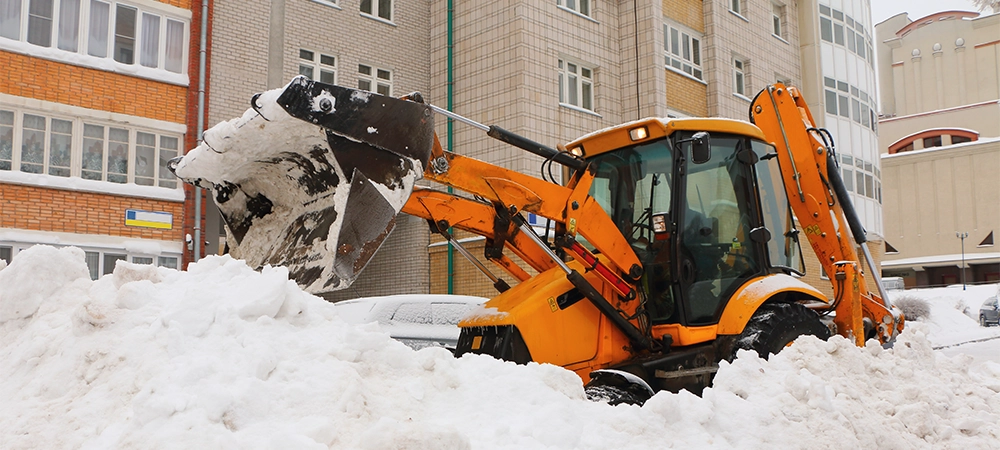 Tractor clean the yard from snow in the city.