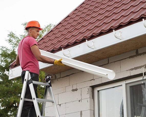 worker installing eavestrough on home roof