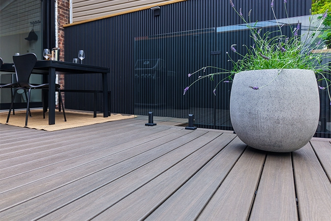 close up view of yard trex deck, plant pot, seating area and modern fence
