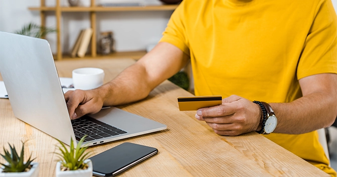 cropped view of man holding credit card near laptop