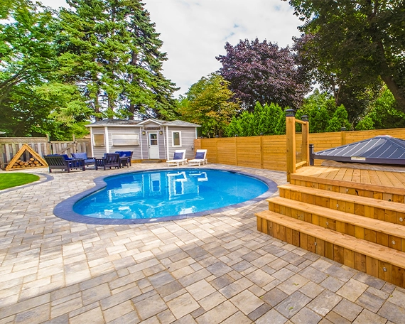 interlocking patio and surface around pool with sodding, wooden deck, fence and carpentry