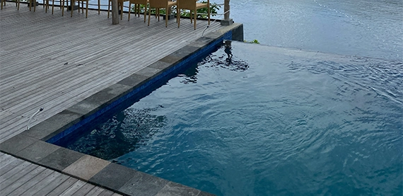 infinity swimming pool with deck and waterfall feature