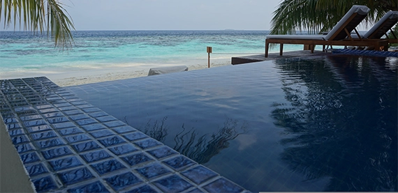 infinity swimming pool with blue tiles and front sea view