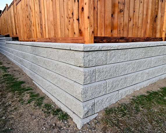 corner view of interlocking retaining wall and wooden fence on it