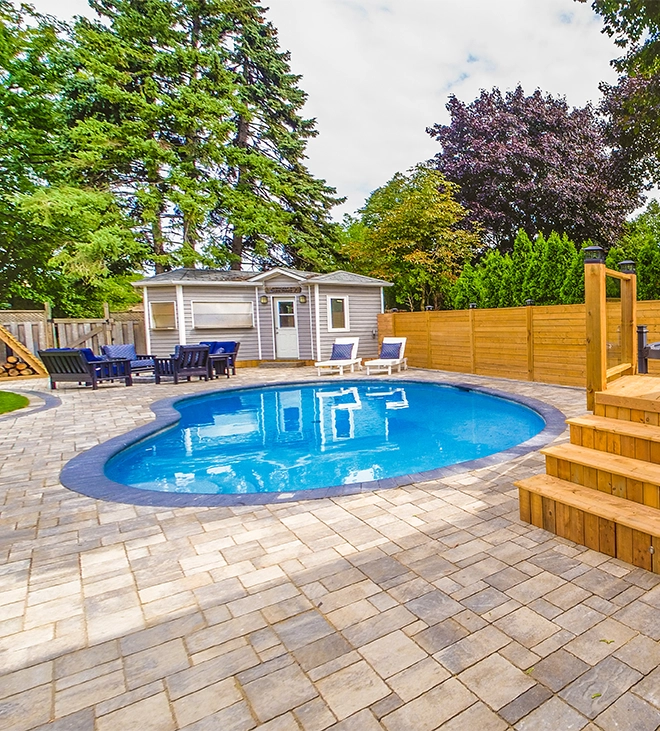 interlocking surface around pool and backyard space, custom carpentry storage room, sitting setup, wooden deck, fence and landscaping