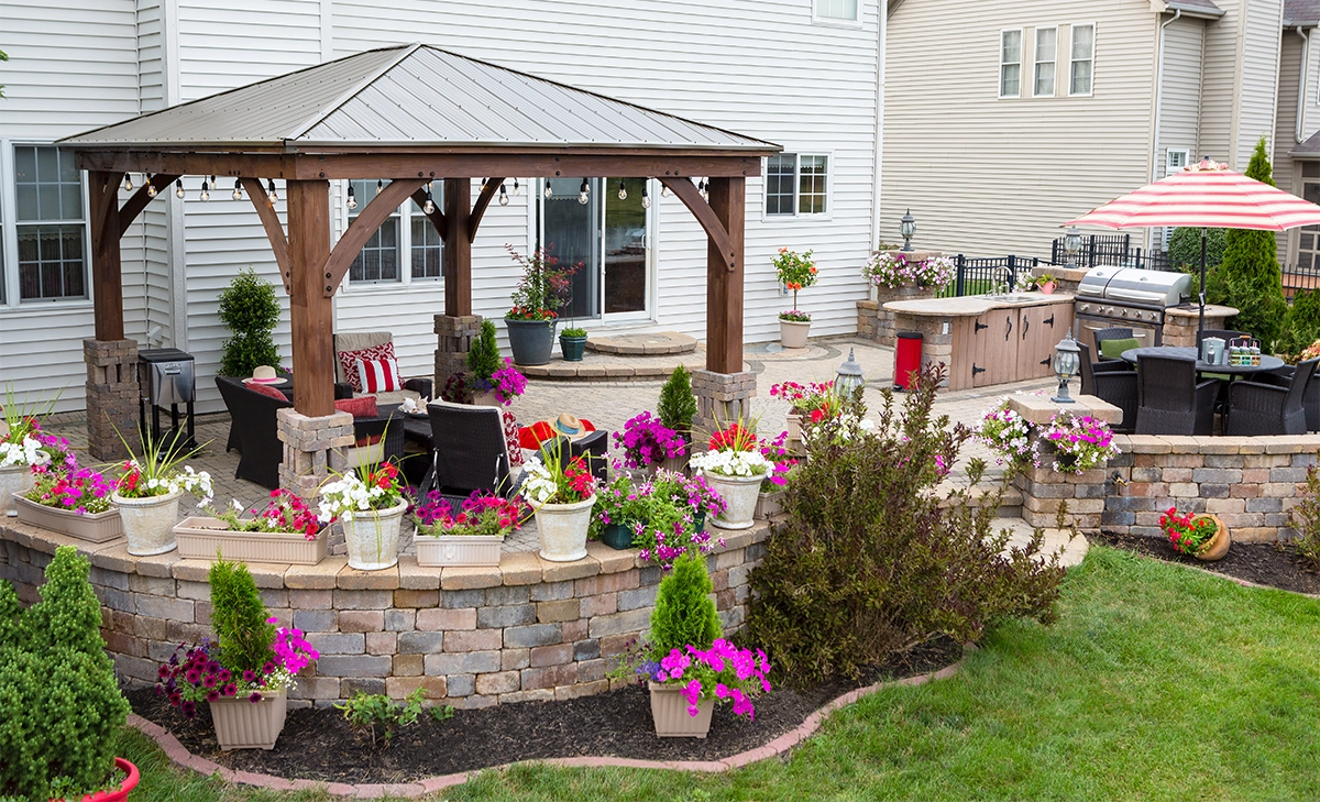 home backyard view, paver patio, mixed colours retaining wall blocks, cabana and open kitchen with dinning area