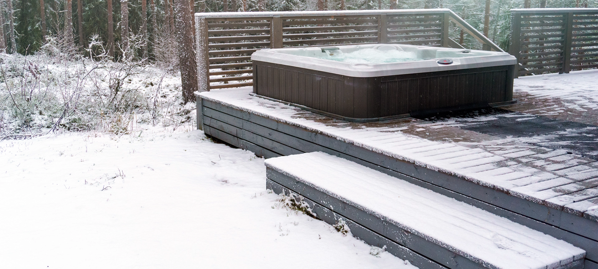 Modern outdoor hot tub on a wooden deck in the cold winter day