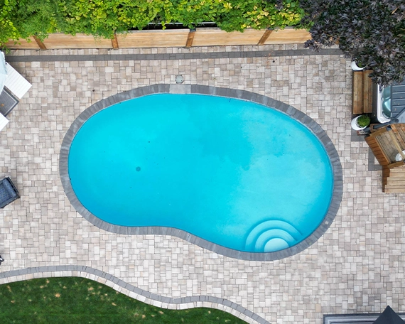 interlocking patio and surface around pool with sodding, wooden deck, fence