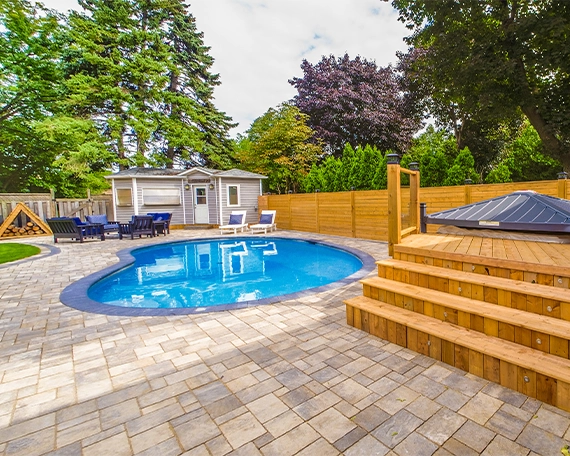 interlocking patio and surface around pool with sodding, wooden deck, fence and carpentry