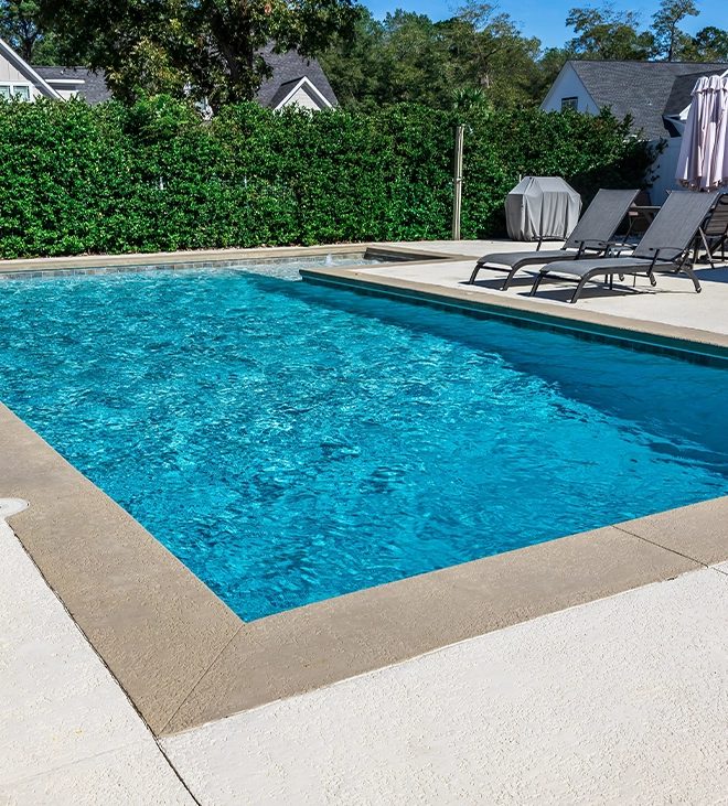 inground salt water pool system with pool coping and concrete deck, surrounding covered with landscaping