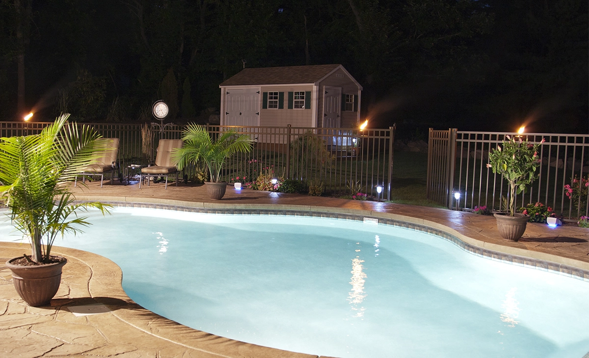 salt water pool in home backyard covered by aluminium fence, night view