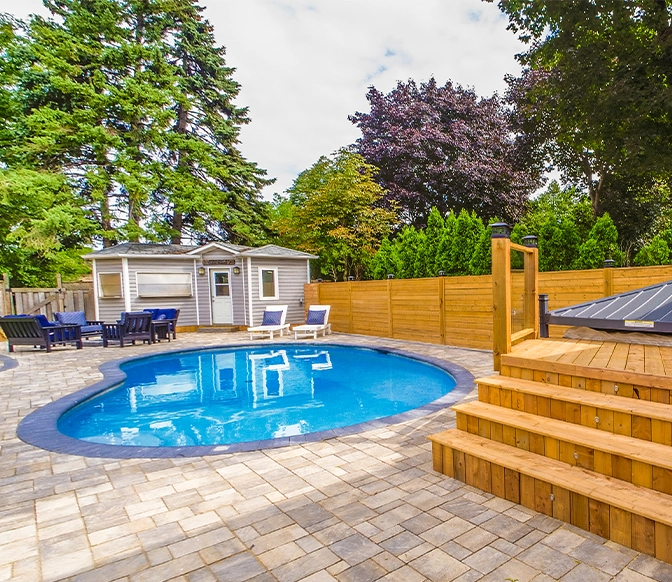 interlocking surface around swimming pool, custom carpentry, wooden deck and seating area in home backyard