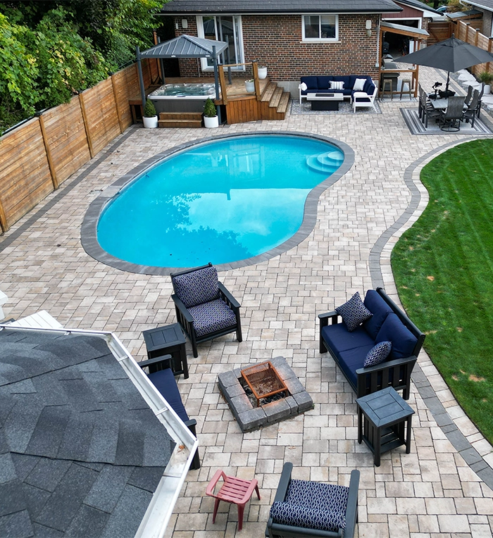 top view of interlocking surface around pool and backyard space, custom carpentry storage room, sitting setup, wooden deck, fence and landscaping