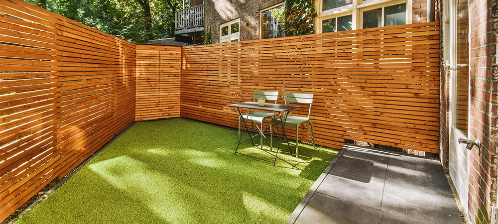 Neat paved patio with sitting area and small garden near wooden fence