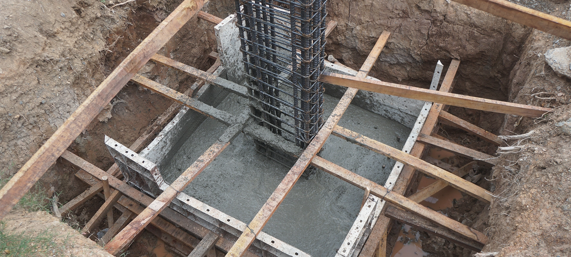 Pouring footing cement in square concrete formwork for foundation work. Deep Foundation Footing.