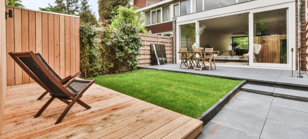 Stylish and well-maintained courtyard of the house with wooden table and chairs and a fresh lawn