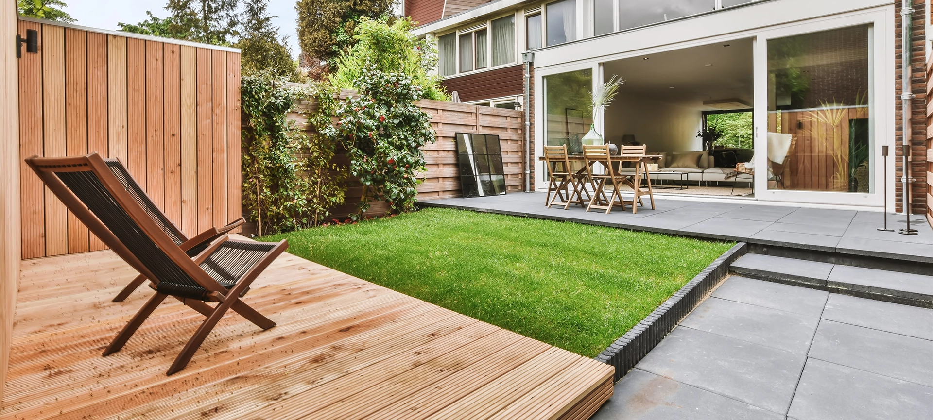 Stylish and well-maintained courtyard of the house with wooden table and chairs and a fresh lawn