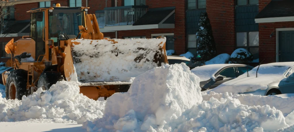 Snow plough truck clearing road after winter snowstorm blizzard for vehicle access