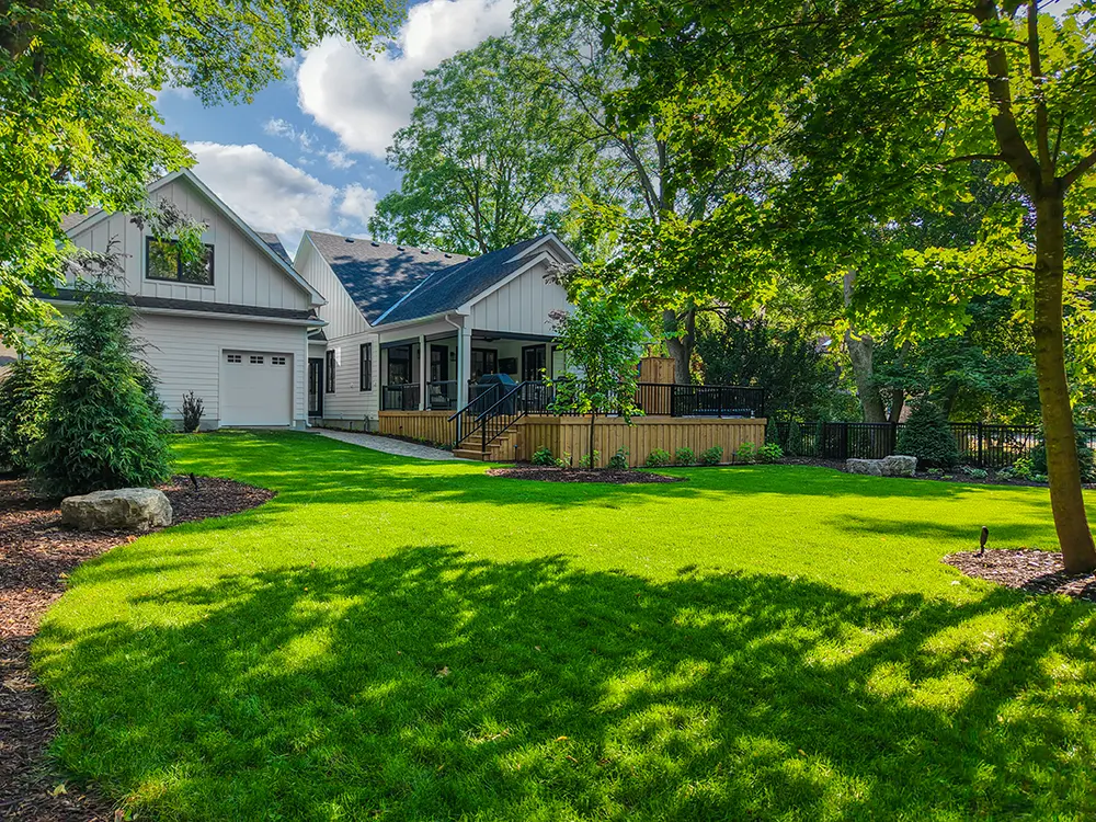big backyard with lots of plants, grass, and a deck
