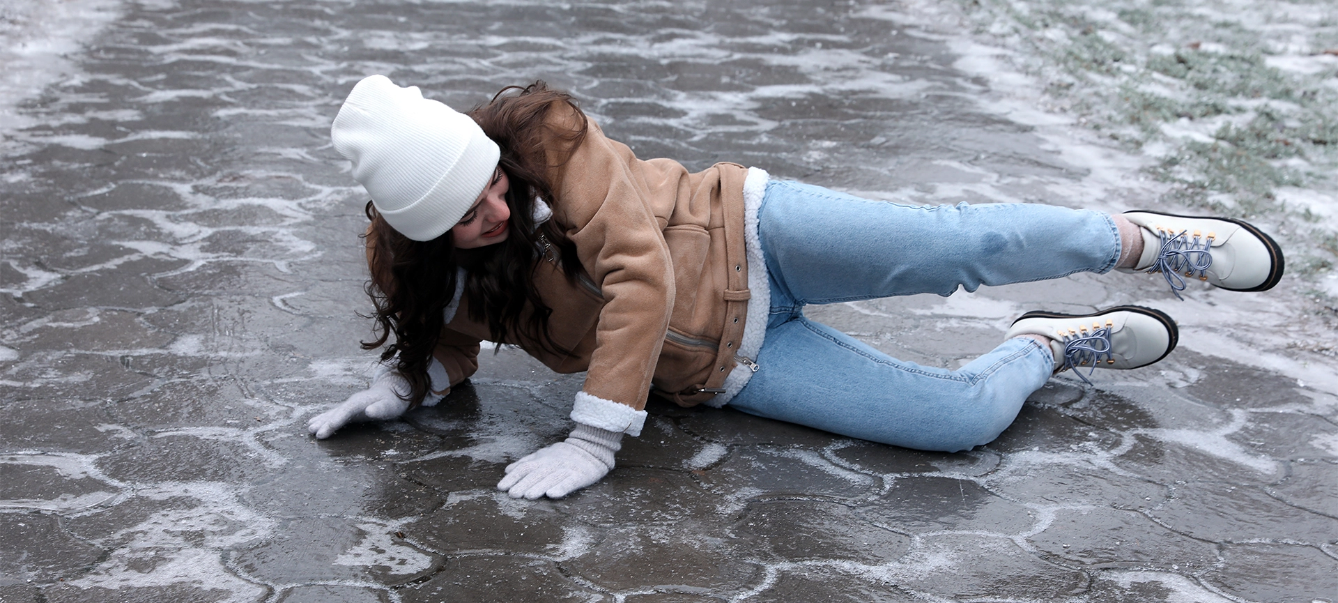 Young woman fallen on slippery icy pavement outdoors