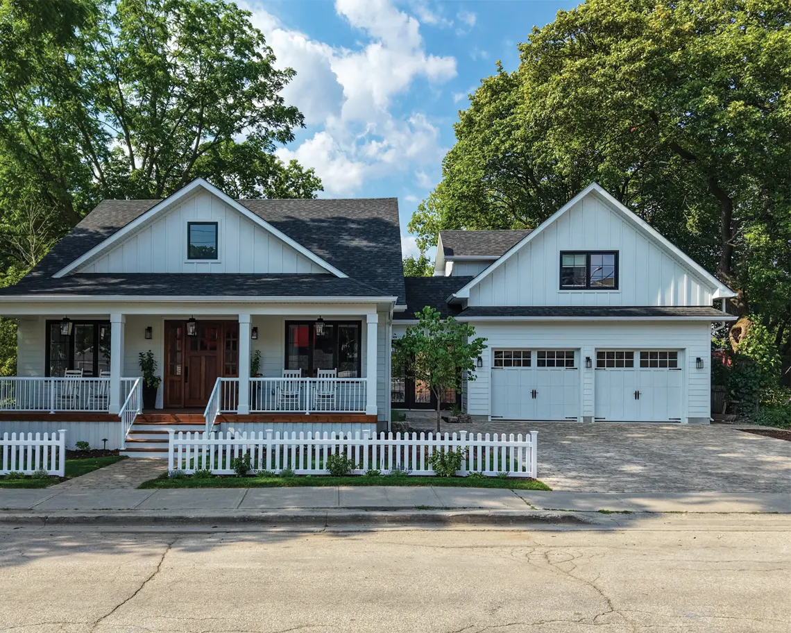 beautiful home with an interlocked driveway and white fence