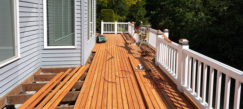 Outdoor wooden deck being remodeled with new red cedar wood floor boards being installed