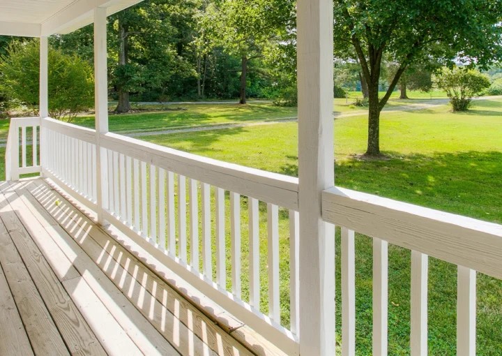 Charming Front Porch With Expansive Yard View And White Railing