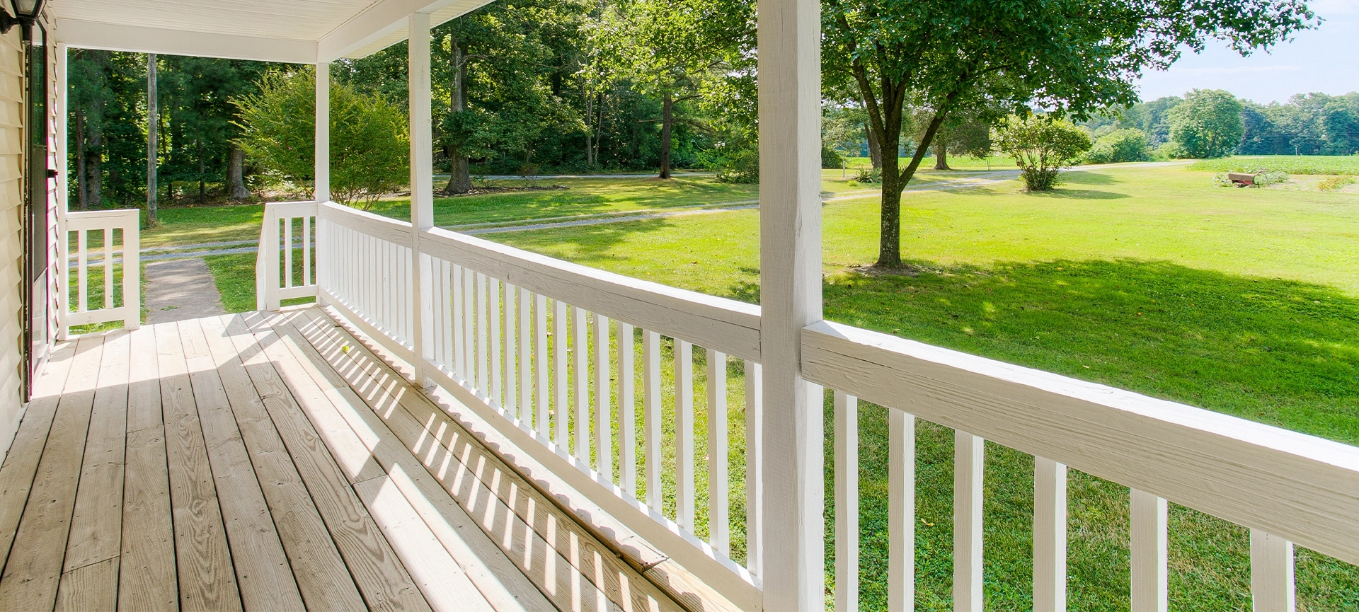 Charming Front Porch With Expansive Yard View And White Railing