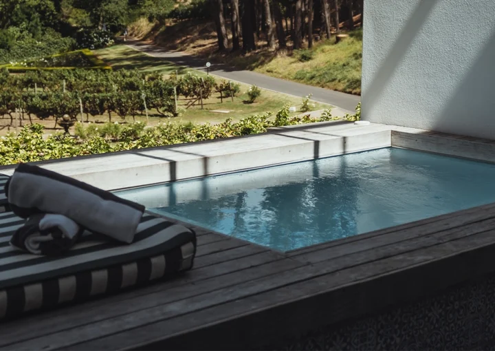 Swimming pool, luxury house exterior at MolenVliet Vineyards Stellenbosch with a small plunge pool on a scenic wooden deck with stunning view over the vineyards during summertime in South Africa.