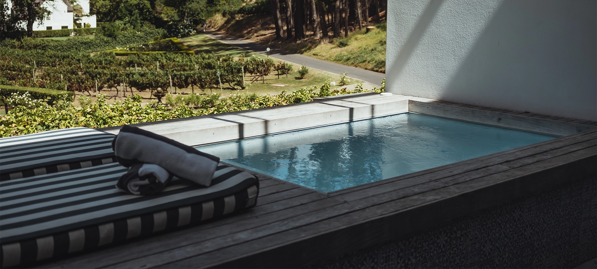 Swimming pool, luxury house exterior at MolenVliet Vineyards Stellenbosch with a small plunge pool on a scenic wooden deck with stunning view over the vineyards during summertime in South Africa.