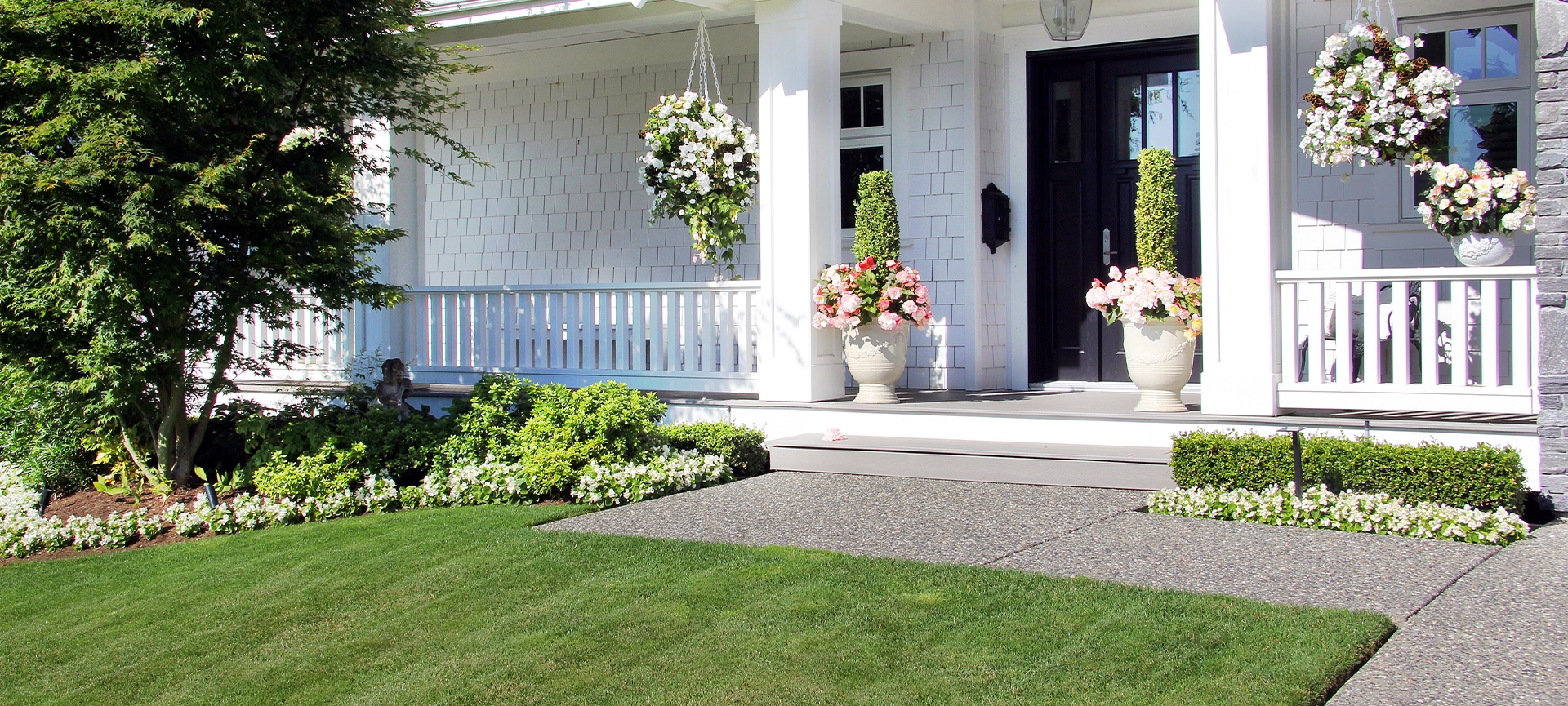 Beautiful new luxury home exterior in summer. Custom house with a porch and professional landscaping in Canada.