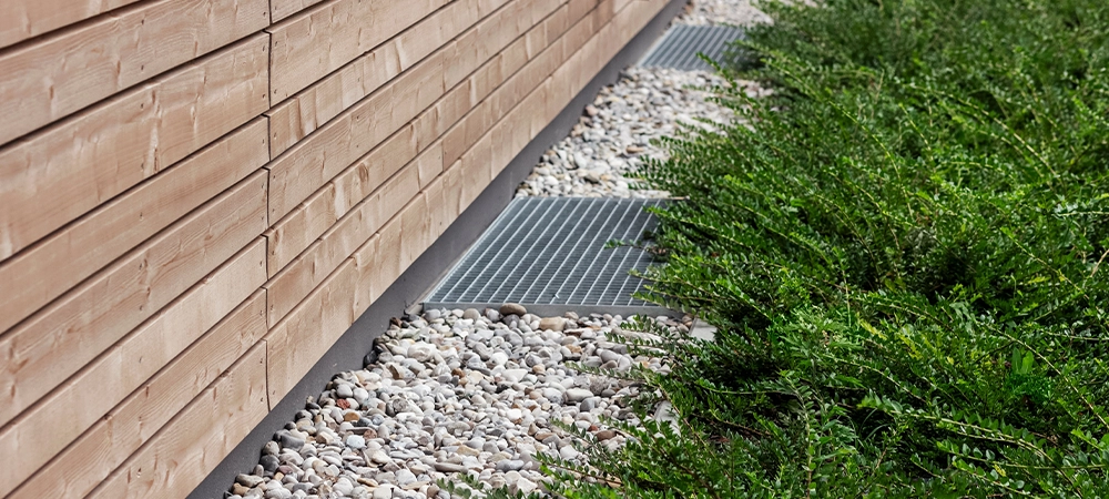 Foundation French Drain Drainage Systems. Drain Stone Layer or Crushed Stone with Drainage Grate Outdoor Facade Exterior Building.