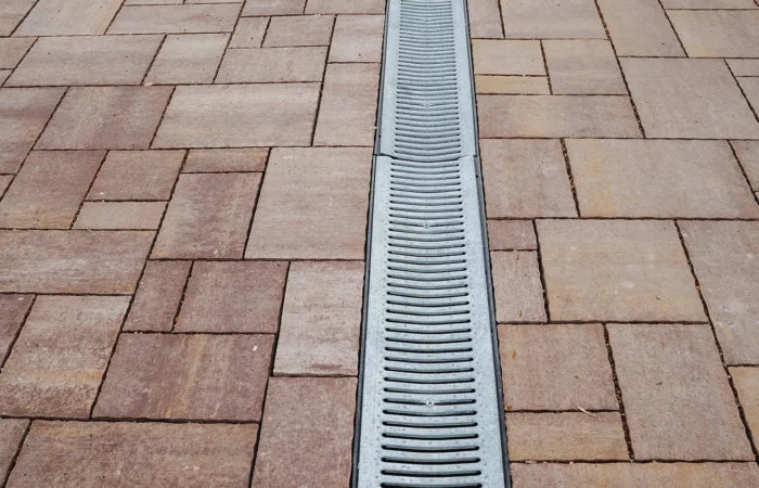 This image shows a closeup of a brick driveway drain, highlighting the intricate brick textures and the cleverly integrated drainage system that enhances both functionality and aesthetics