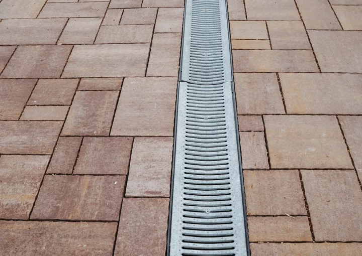 This image shows a closeup of a brick driveway drain, highlighting the intricate brick textures and the cleverly integrated drainage system that enhances both functionality and aesthetics