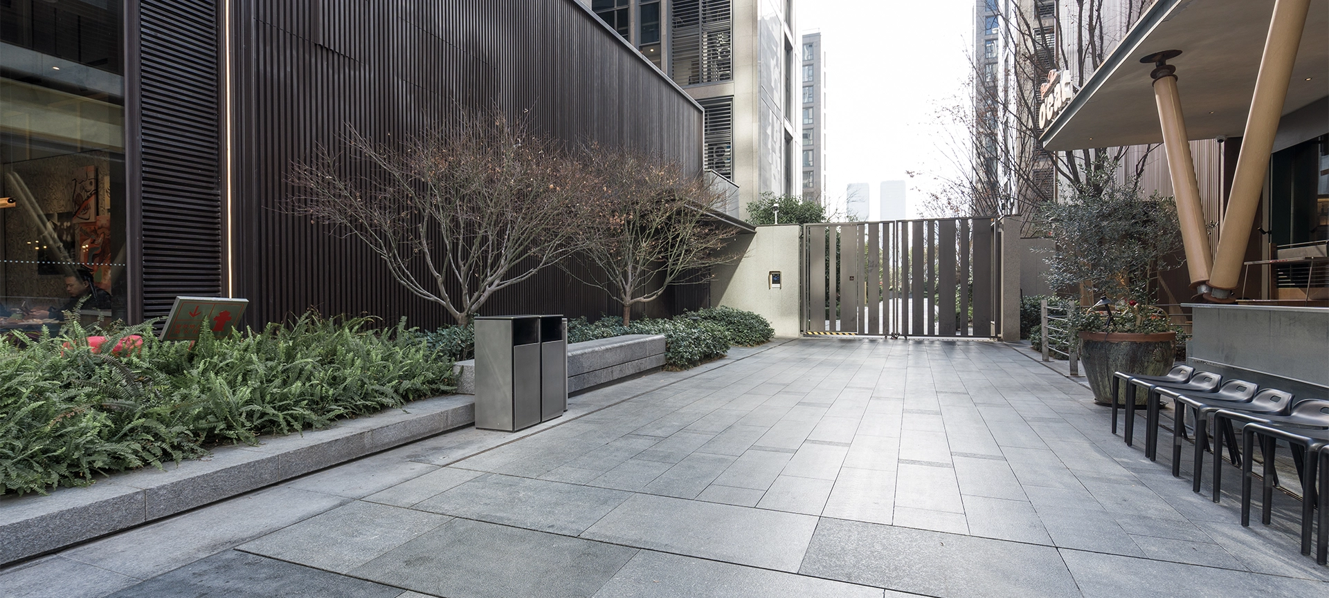 Modern urban commercial district courtyard with paved walkway and landscaped greenery