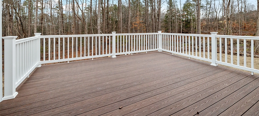 The decking boards of a porch with white railings in a suburb house