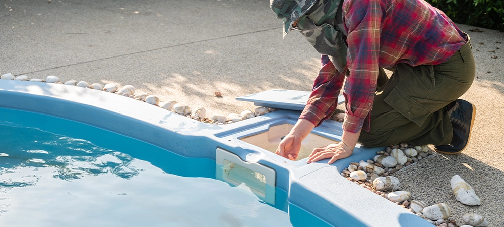 Technician trying to check pool skimmer. Its purpose is to clean the surface by sucking water into a conduit system. It is an essential part of any pool to ensure proper operation and maintenance.