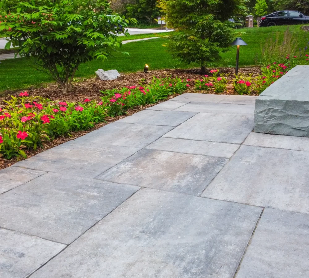 paved patio with lots of colourful flowers and grass