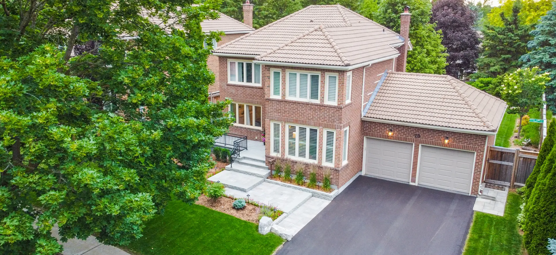 large house with paved driveway and interlock patio