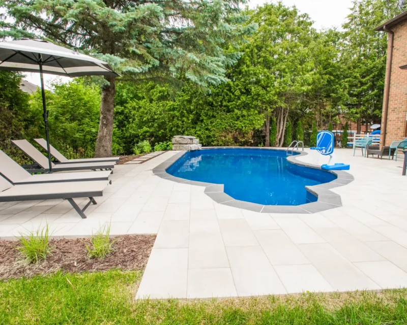 Paver walkway with stepping stones beside a pool and waterfall