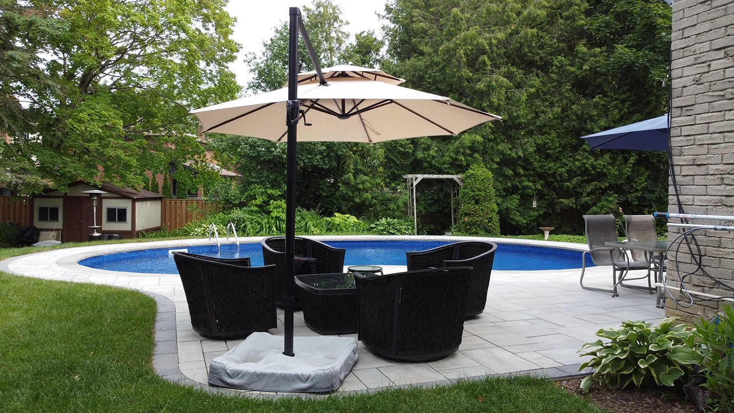 patio with umbrella and chairs and pool in the back