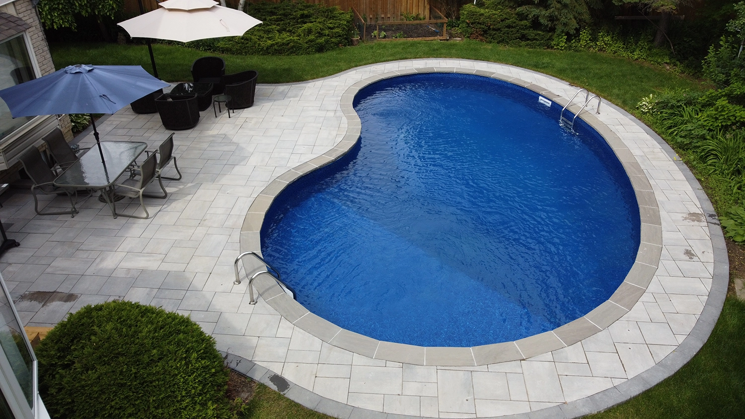 aerial shot of a backyard with patio furniture and a pool